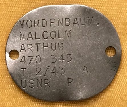 Warrant Officers Malcolm Arthur Vordenbaum 470345 US Navy. He was born on August 2, 1915, in San Antonio, Texas. The son of Max A Vordenbaum and Lydia M Vordenbaum of 430 Grant Street Wichita Falls, Texas. The family moved to Wichita Falls in 1918 when Max was the supervisor of the building of the initial seven buildings of the State Hospital. Malcolm graduated from Wichita Falls High School in 1932. He enrolled as a mechanical engineering student at Texas A&M. In 1936 he joined the firm of J. E. Morgan & Sons, a large building construction company. He married Ferne Vernoye Tracy of La Veda Colorado, on March 1, 1941 in Albuquerque, New Mexico. He was still worked at J E Morgan and Sons, when he entered the US Navy Seabees with his brother in 1942 around the age 27. At the time of his enlistment he was 6-foot 1 inch tall had blue eyes, blonde hair and weighed 200 pounds. He trained in Norfolk VA with the Seabees. In 1943 Vordenbaum was an extra on the 1944 movie “The Fighting Seabees” starring John Wayne and Susan Hayward. Malcolm Vordenbaum was very proud of this and was especially proud that he had a cameo appearance in the movie. At the end of the film after John Wayne has been killed, Malcolm Vordenbaum can be seen on a ridge shooting down at the enemy.  Malcolm Vordenbaum had taped TEXAS on his back and moved right and left. Also Vordenbaum had the honor of being chosen to crown Susan Hayward, as “Queen of the Seabees.” On the day of the photo shoot he spent a day at Smiley Barnett's ranch making publicity photos with Susan Hayward. After this he was deployed to the Pacific Theater of Operations with a Seabees Unit and served in the Marshalls and Gilberts. He was awarded the  The American Campaign Medal, the Asiatic Pacific Campaign Medal (PTO), The Good Conduct Medal, and the World War Two Victory Medal. In 1957 he returned to Wichita Falls in and joined his father and brother in M.A. Vordenbaum & Sons Construction Co. Malcolm also served for over 50 years as a Mason and was active in the Maskat Shrine. He served as President of the West Texas Chapter of the Associated General Contractors. He was very well known for his track work as a model railroader. He died on December 16, 2004, in Wichita Falls, Texas, at the age of 89.